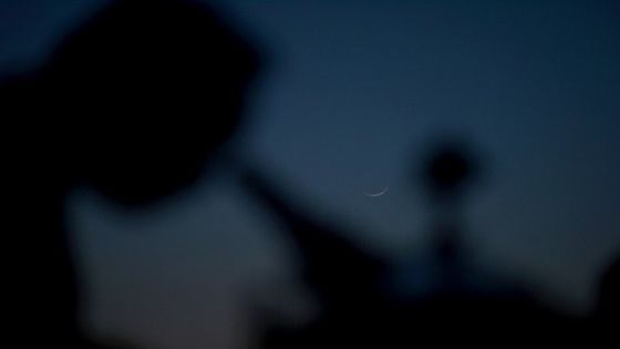 A member of Pakistan Ramadan moon-sighting committee, looks through a telescope for the new moon (C) that signals the start of the Muslim fasting month of Ramadan in Karachi on April 13, 2021. (Photo by Rizwan TABASSUM / AFP)