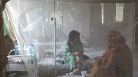 A patient suffering from dengue fever chats with a woman while sitting under a mosquito net inside a dengue and malaria ward at the Sindh Government Services Hospital in Karachi, Pakistan September 21, 2022. REUTERS/Akhtar Soomro