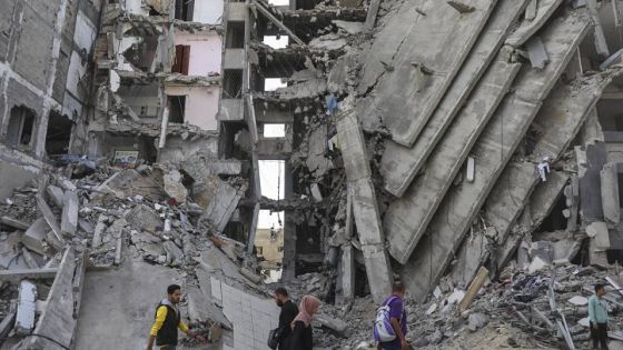 Palestinians walk through destruction in Gaza City on Friday, Nov. 24, 2023, as the temporary ceasefire between Israel and Hamas took effect. (AP Photo/Mohammed Hajjar)