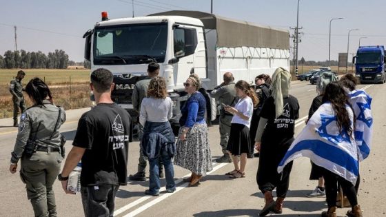 Israeli border guards and right-wing protesters stand by as Jordanian trucks carrying humanitarian aid supplies pass by while arriving on the Israeli side of the Kerem Shalom border crossing with the Gaza Strip in southern Israel on April 16, 2024, amid the ongoing conflict in the Palestinian territory between Israel and the militant group Hamas. (Photo by Menahem Kahana / AFP)