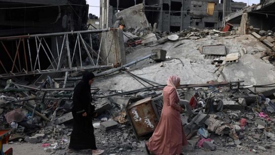 TOPSHOT - Women walk past a destroyed building in the aftermath of Israeli bombing in Rafah in the southern Gaza Strip on October 28, 2023. Since the October 7 Hamas attack on Israel, the health ministry in the Palestinian enclave said more than 7,300 Palestinians have been killed by Israel's relentless retaliatory bombardments, mainly civilians and many of them children. (Photo by SAID KHATIB / AFP)