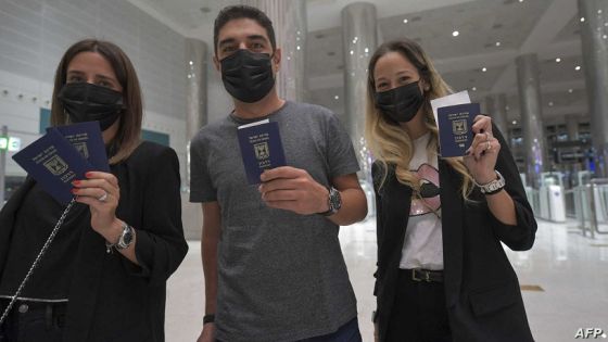 Israelis pose for a picture with their passports upon arrival from Tel Aviv to the Dubai airport in the United Arab Emirates, on November 26, 2020, on the first scheduled commercial flight operated by budget airline flydubai, following the normalisation of ties between the UAE and Israel. (Photo by Karim SAHIB / AFP)