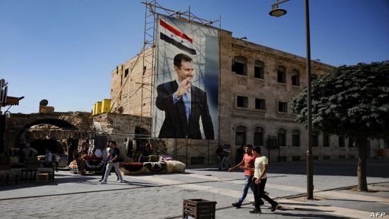 (FILES) In this file photo taken on September 27, 2019 during a guided tour with the Russian army shows men walking past a poster of Syrian President Bashar al-Assad in the old city of Aleppo. - Syria is to hold a presidential election on May 26, the parliament speaker announced today, the country's second in the shadow of civil war, seen as likely to keep President Bashar Al-Assad in power. (Photo by Maxime POPOV / AFP)