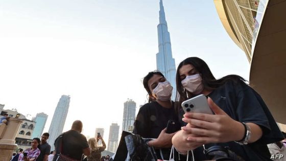 Women wearing protective masks pose for a "selfie" picture on a cell phone in front of Burj Khalifa, the tallest structure and building in the world since 2009 (total heigh with antenna of 829.8 metres), in the city centre of the Gulf emirate of Dubai on March 8, 2020. (Photo by GIUSEPPE CACACE / AFP)