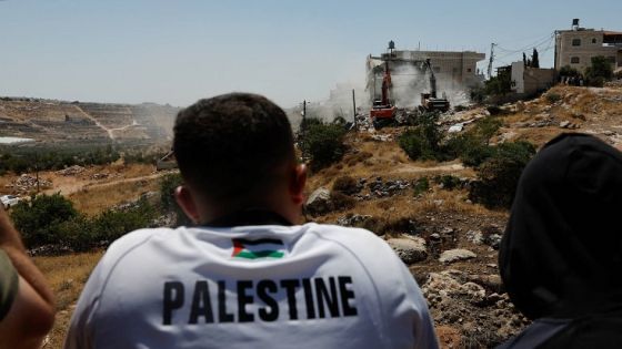 Palestinians watch as Israeli machinery guarded by Israeli forces demolishes a Palestinian house near Hebron, in the Israeli-occupied West Bank, July 11, 2024. REUTERS/Mussa Qawasma