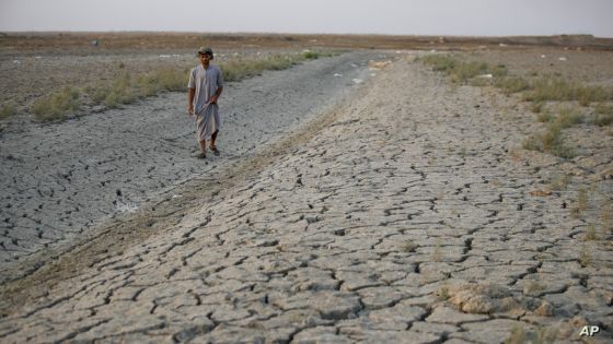 A fisherman walks across a dry patch of land in the marshes of southern Iraq which has suffered dire consequences from back to back drought and rising salinity levels, in Dhi Qar province, Iraq, Friday Sept. 2, 2022. (AP Photo/Anmar Khalil)