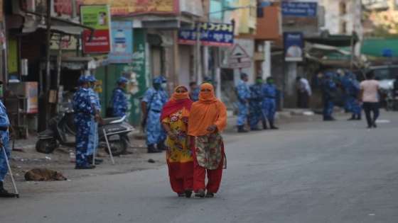 Muslim women walk in front of Para-Military personnel from the Rapid Action Force (RAF) as they wear facemasks during a government-imposed nationwide lockdown as a preventive measure against the COVID-19 coronavirus in Ahmedabad on April 12, 2020. (Photo by SAM PANTHAKY / AFP) (Photo by SAM PANTHAKY/AFP via Getty Images)