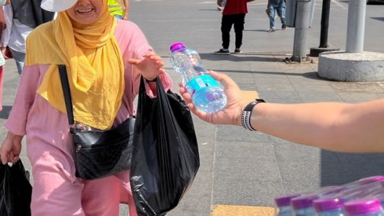 A volunteer distributes water to people in a street in Algiers, during a heatwave, Algeria July 19, 2023. REUTERS/Abdelaziz Boumzar