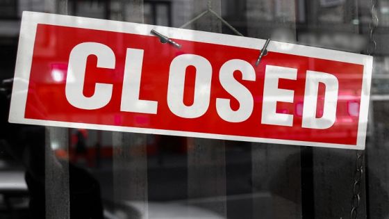 Closed sign in a shop showroom with reflections - red sign over desaturated background