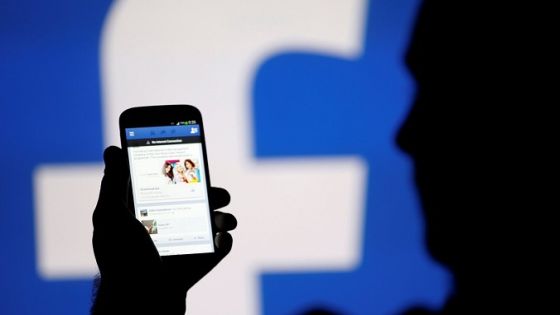 FILE PHOTO: A man is silhouetted against a video screen with an Facebook logo as he poses with an Samsung S4 smartphone in this photo illustration August 14, 2013. REUTERS/Dado Ruvic/File Photo