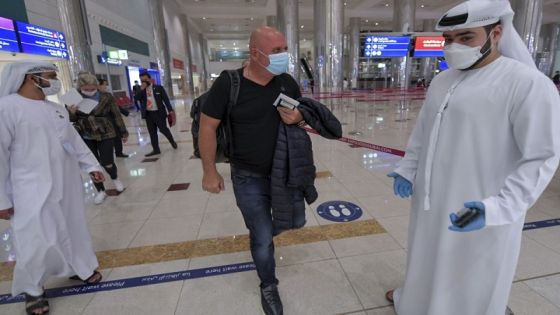 An Israeli man walks past Emirati staff after passport control upon arrival from Tel Aviv to the Dubai airport in the United Arab Emirates, on November 26, 2020, on the first scheduled commercial flight operated by budget airline flydubai, following the normalisation of ties between the UAE and Israel. (Photo by Karim SAHIB / AFP)