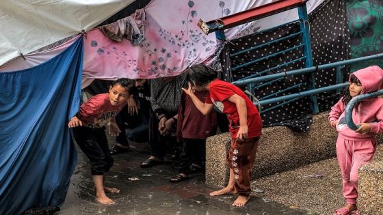 Children take shelter from the rain under a tent at a school run by the United Nations Relief and Works Agency for Palestine Refugees in the Near East (UNRWA) in Rafah in the southern Gaza Strip on November 14, 2023, where internally displaced Palestinians have taken refuge amid ongoing battles between Israel and the Palestinian militant group Hamas. (Photo by SAID KHATIB / AFP)