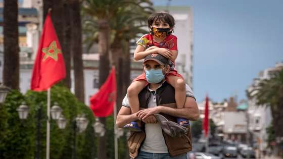 A mask-clad father carries his son on his shoulder as they walk in the centre of Morocco's capital Rabat amid the ongoing COVID-19 pandemic, on June 16, 2020. (Photo by FADEL SENNA / AFP) (Photo by FADEL SENNA/AFP via Getty Images)