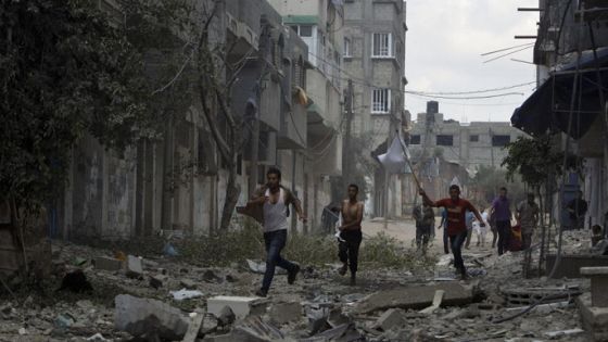 Civilians run in a street in Gaza's eastern Shejaiya district on July 20, 2014. At least 40 people were killed and nearly 400 wounded in Israeli shelling of Gaza's northeastern Shejaiya district overnight, medics said. AFP PHOTO / MAHMUD HAMS