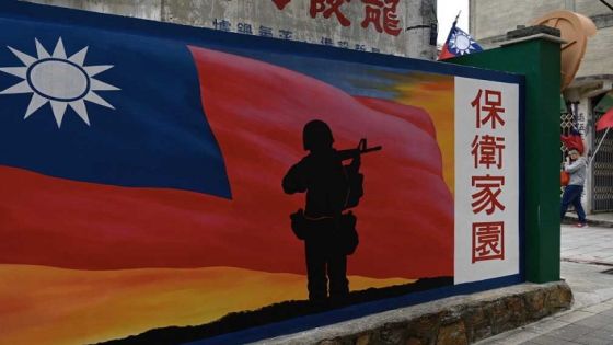 This photo taken on October 21, 2020 shows a tourist (R) walking past a mural painted on a wall on Taiwan's Kinmen islands, which lie just 3.2 kms (two miles) from the mainland China coast (in background) in the Taiwan Strait. - The tank traps on the beaches of Kinmen Island are a stark reminder that Taiwan lives under the constant threat of a Chinese invasion -- and fears of a conflict breaking out are now at their highest in decades. (Photo by Sam Yeh / AFP) / TO GO WITH Taiwan-China-US-politics-military-Kinmen,FOCUS by Amber WANG and Jerome TAYLOR