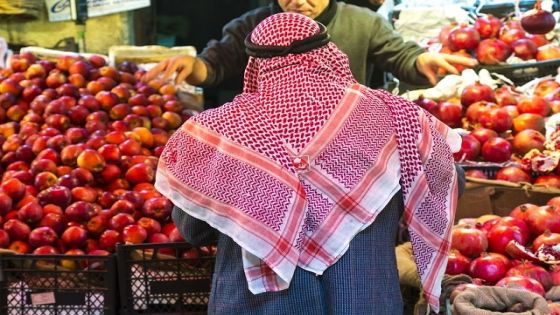 Arab man waerinf Keffiyeh buying apples in market, Amman, Jordan